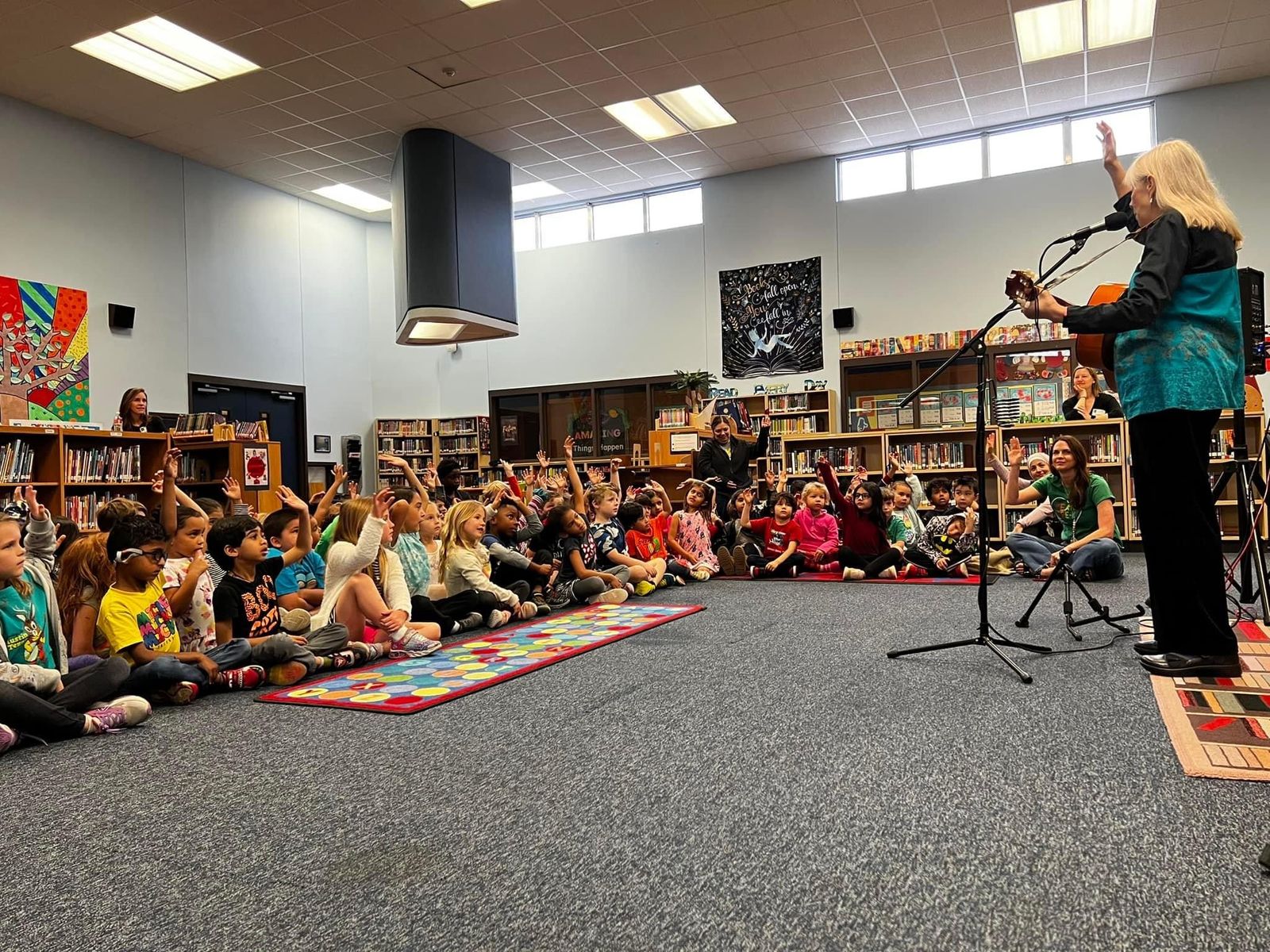 sue leading a performance with a group of children in a school library