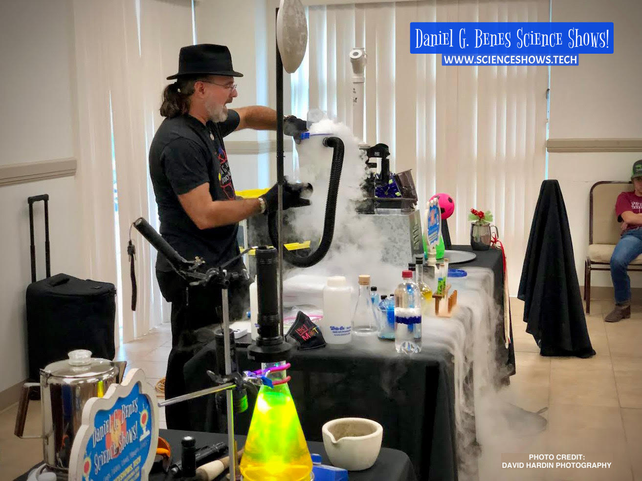 daniel performing a science show with a table full of science equipment